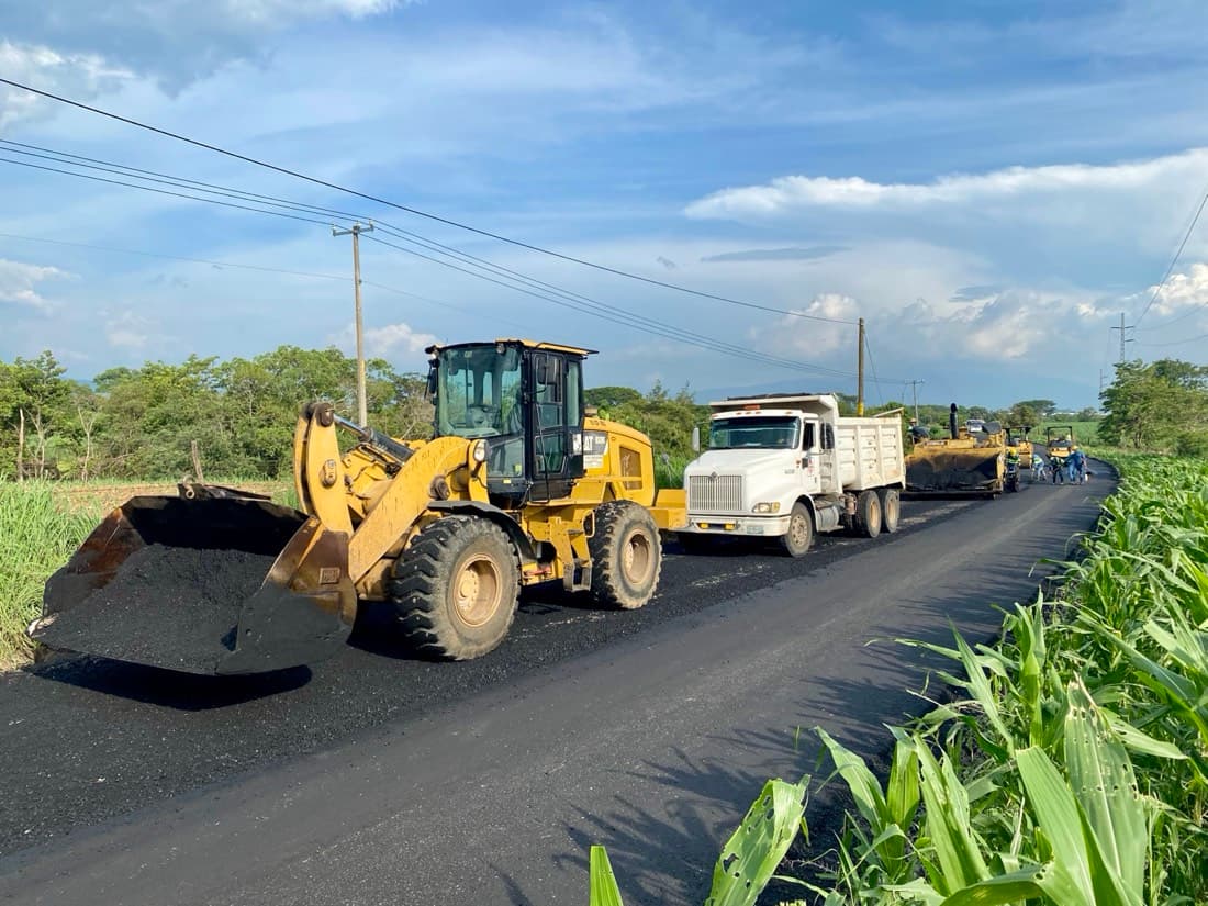 Cargador frontal, dompe y pavimentadora trabajando juntos en obra de pavimentación