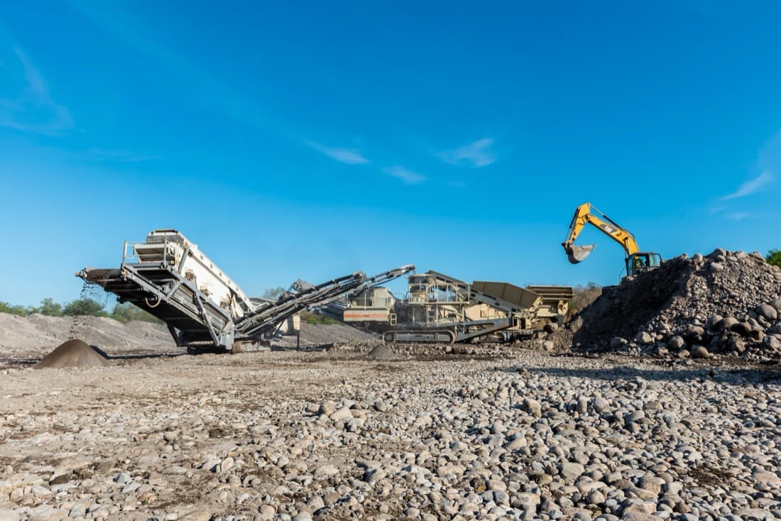 Trituradora y excavadora Caterpillar procesando agregados pétreos